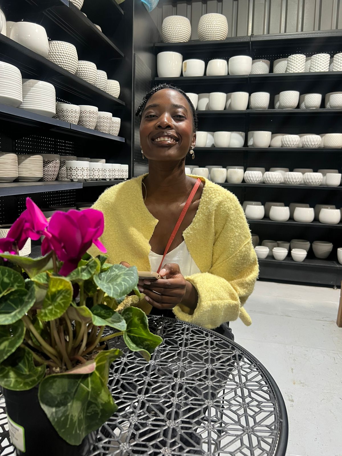 Tshego laughing behind a shelf of white ceramic pots
