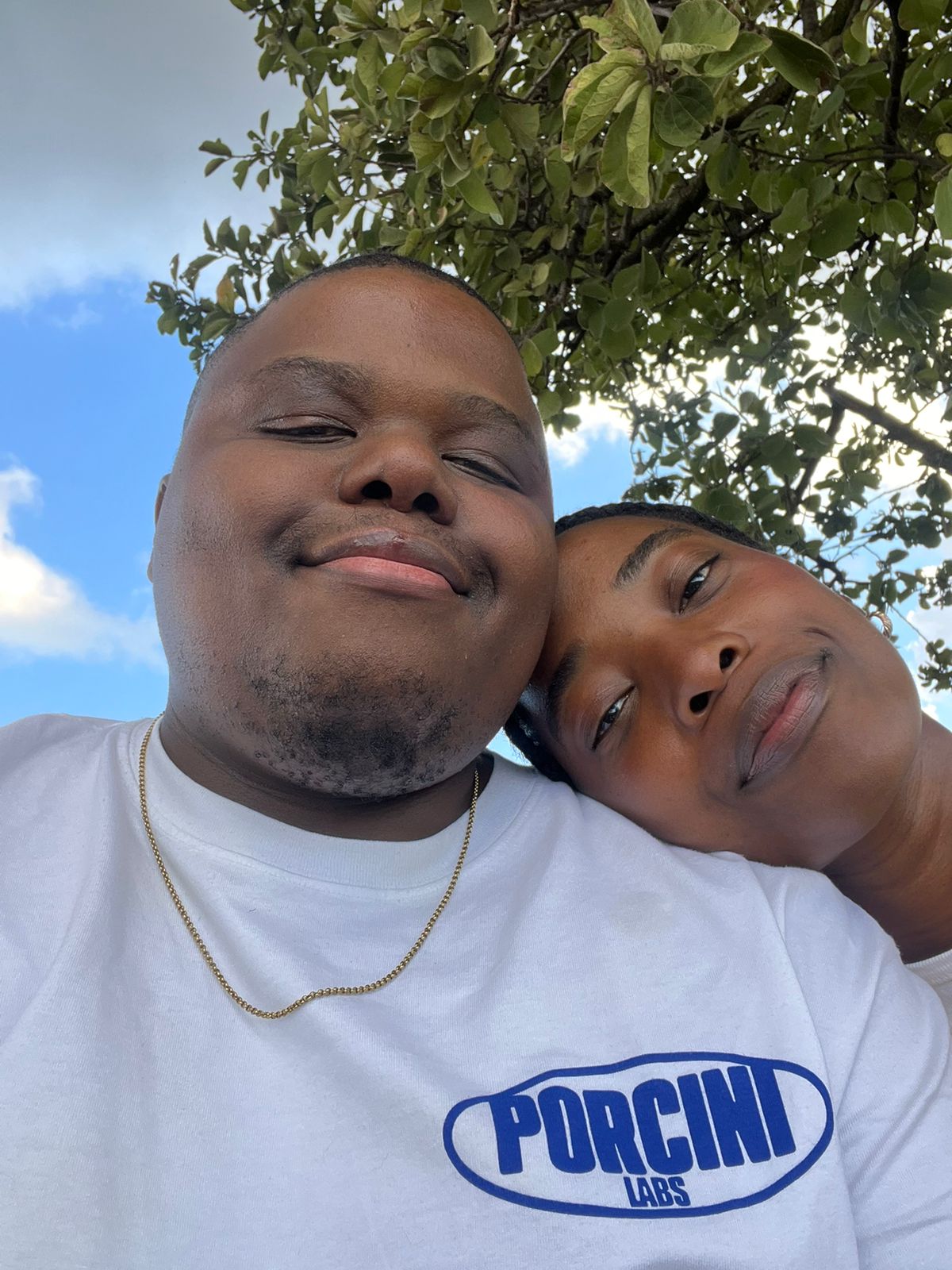 Your head resting on my shoulder under a tree, blue sky behind us